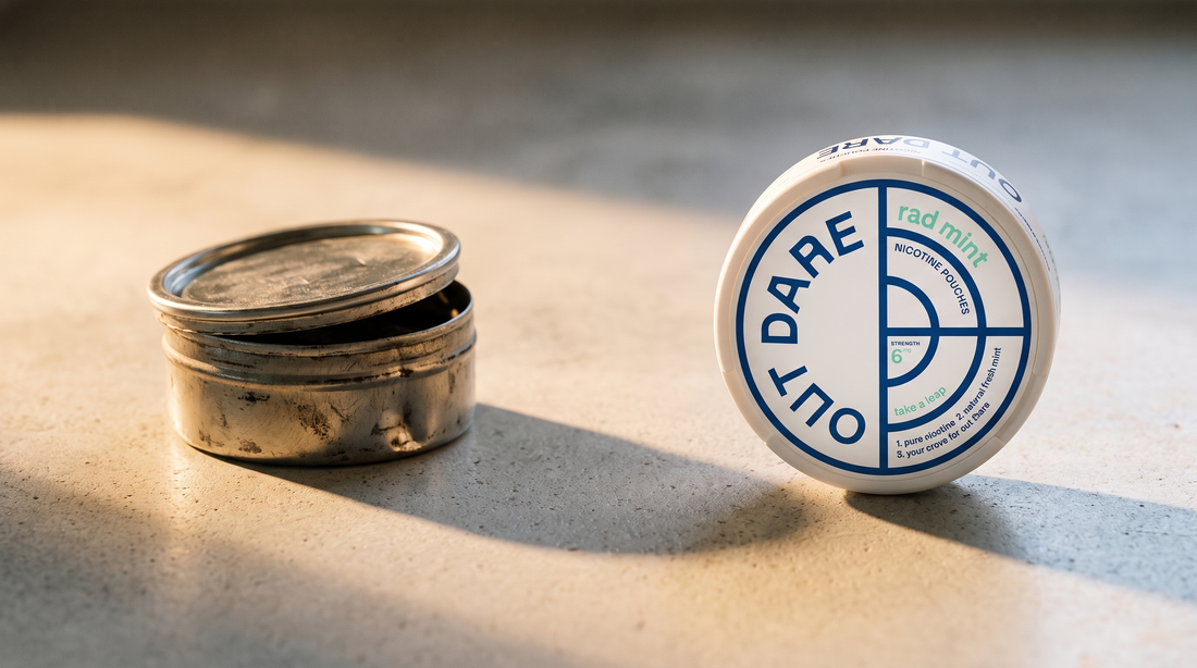 Worn unbranded snus can beside a clean round OutDare nicotine pouch can on a concrete worktop