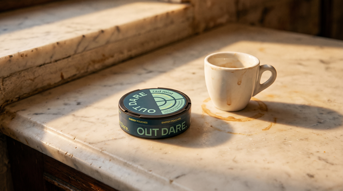 OutDare Energy Pouches can beside a small espresso cup on a worn marble Spanish café counter