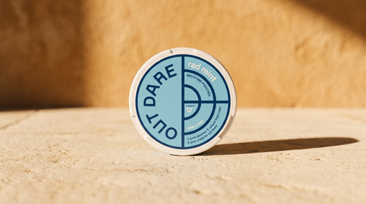 Round nicotine pouch can resting on a sunlit limestone surface with a warm ochre wall behind