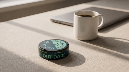 Round flat Energy Pouches can on a home-office desk with a cold coffee mug blurred behind it