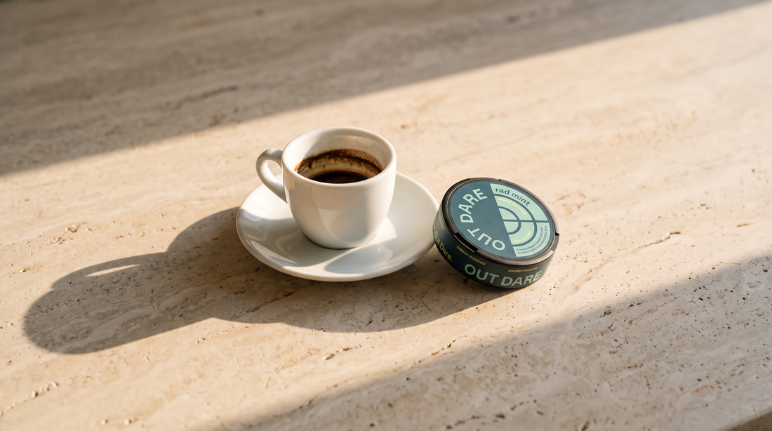 An espresso cup beside a can of caffeine pouches on a pale Italian stone surface