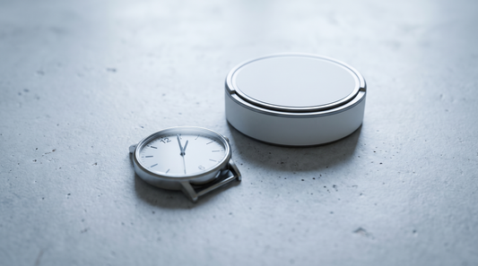 An analogue wristwatch showing half past twelve beside a nicotine pouch can on pale concrete
