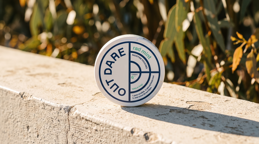 OutDare nicotine pouch can on a sun-bleached concrete outdoor surface in strong daylight