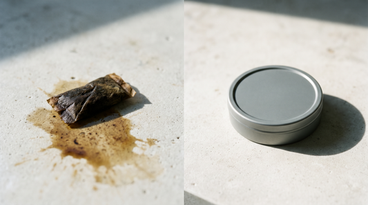 A crumpled brown snus pouch beside a clean lidded nicotine pouch can on pale stone