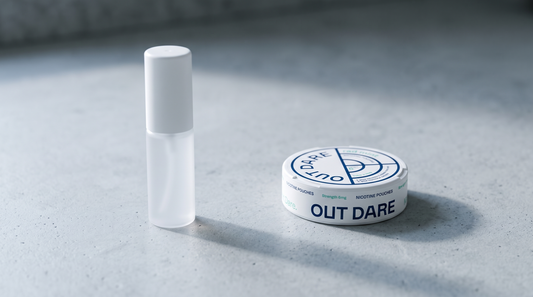 A nicotine spray bottle beside a round nicotine pouch can on a pale concrete worktop