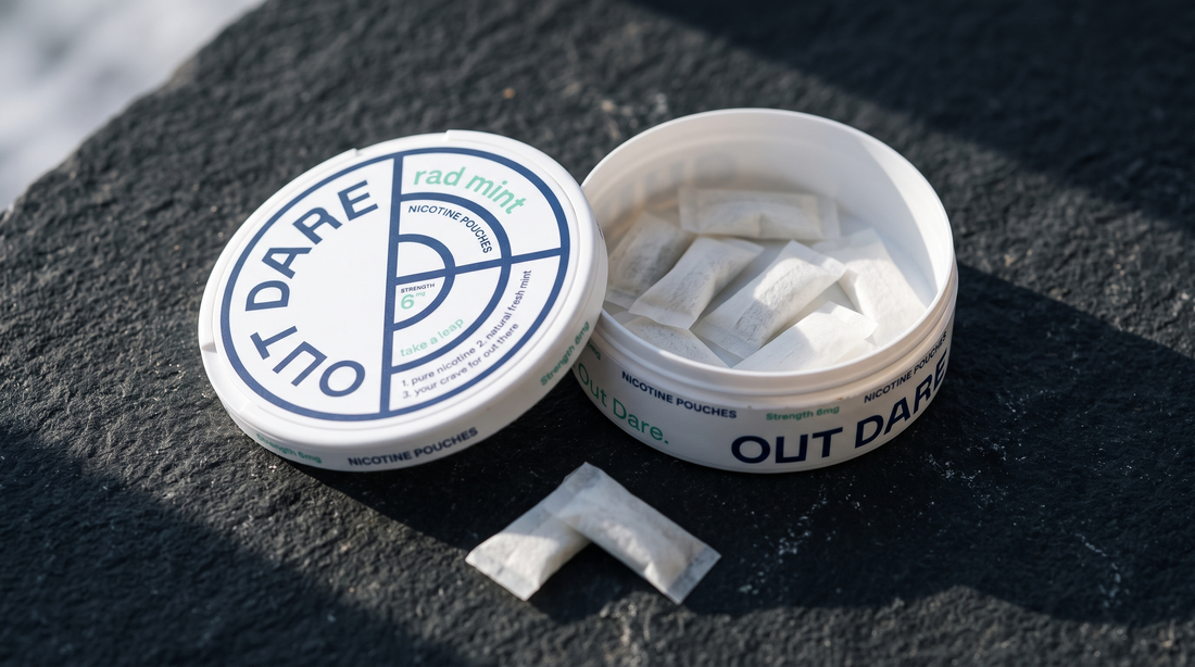 An open nicotine pouch can on dark volcanic stone with white pouches visible inside