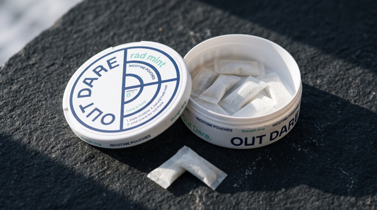 An open nicotine pouch can on dark volcanic stone with white pouches visible inside