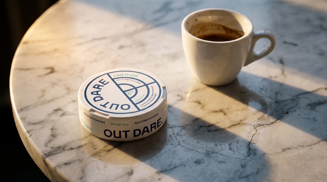 An OutDare nicotine pouch can on a marble café table beside an espresso cup