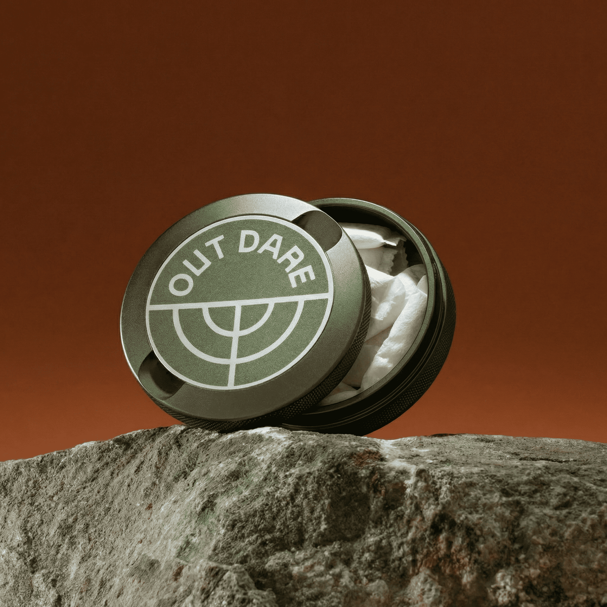 Green OutDare metal can with pouches, on a rock