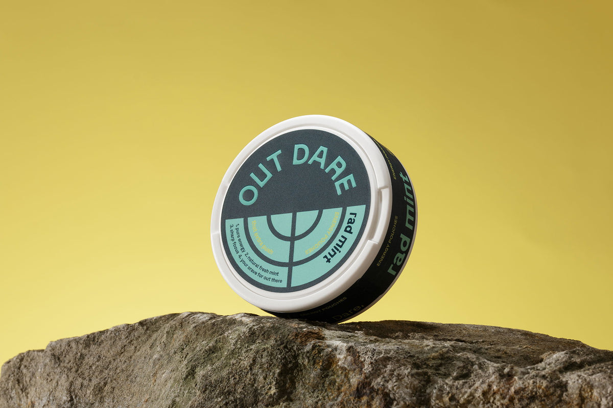 OutDare Energy Pouches can on a rock against a yellow background