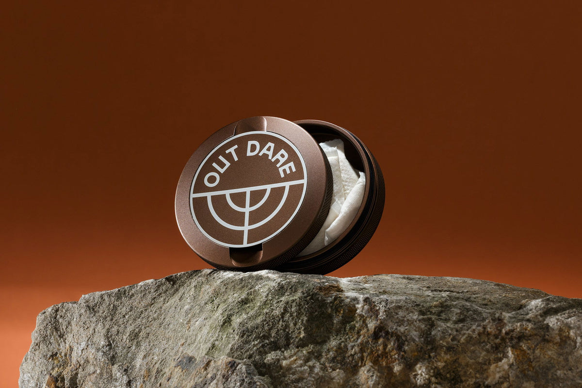 Brown OutDare metal can with pouches, on a rock