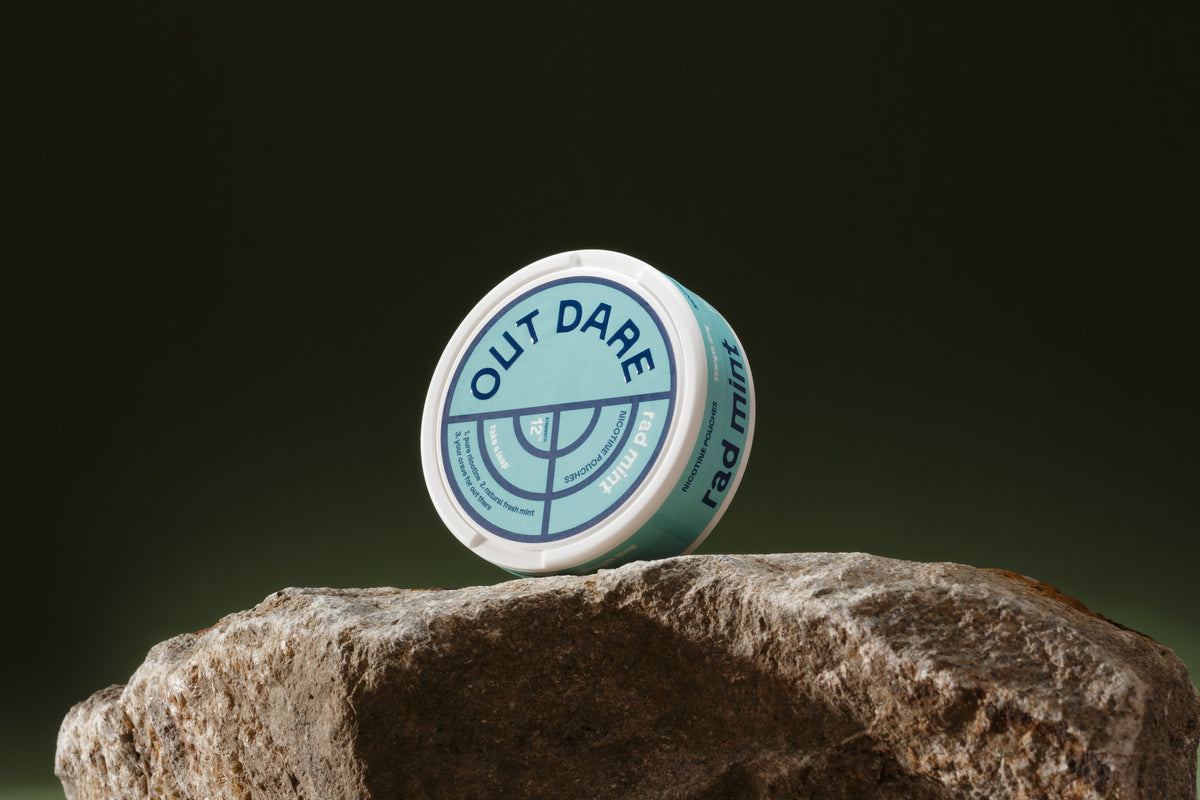 OutDare Nicotine Pouches 12 mg can on a rock against a dark background