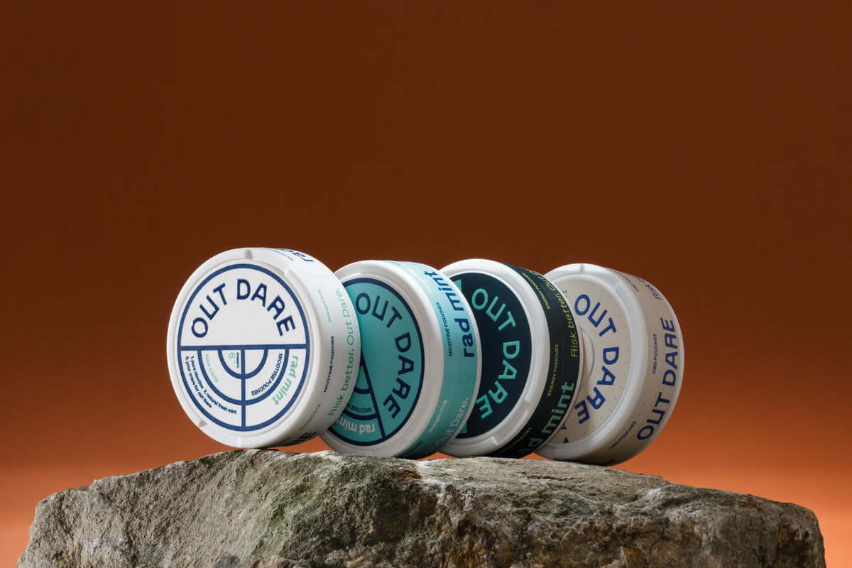 OutDare Nicotine, Energy and Sleep Pouches cans lined up on a rock